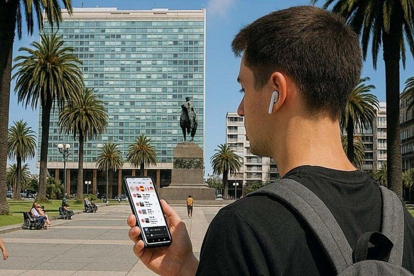 A person holding a smartphone with a map application, palm trees, a statue, and a modern building in the background. 5