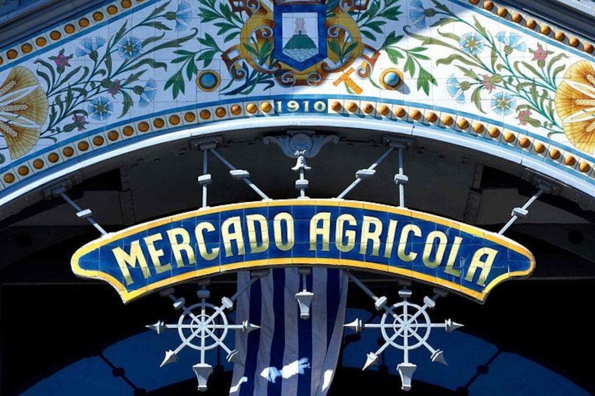 A colorful, ornate sign with the text 'MERCADO AGRICOLA' and a decorative crest above it. 4
