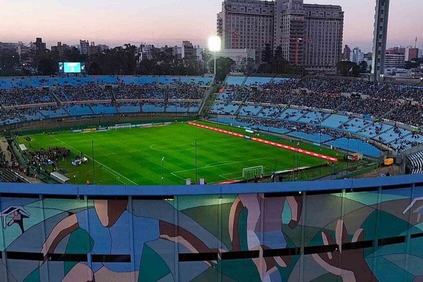 A stadium with a green field, blue seating, and a large crowd. 2