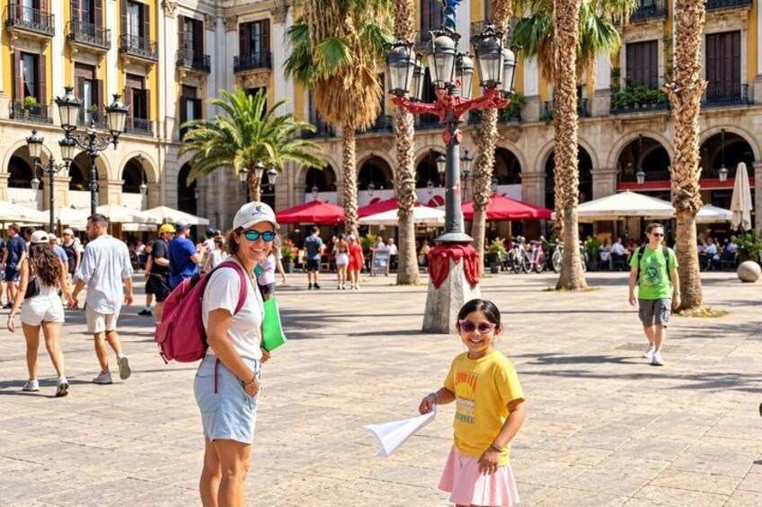 Una plaza pública con palmeras, gente caminando y edificios con arcos. 5
