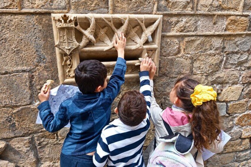 Niños observando un grabado en piedra en una pared. 3