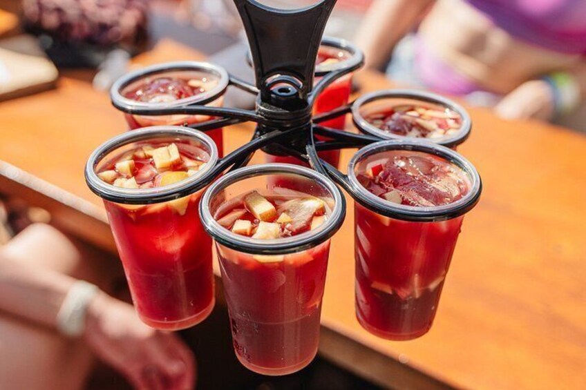 Un distributore di bevande con più bicchieri riempiti di un liquido rosso, forse un cocktail o succo di frutta, e contenenti pezzetti di frutta. 2