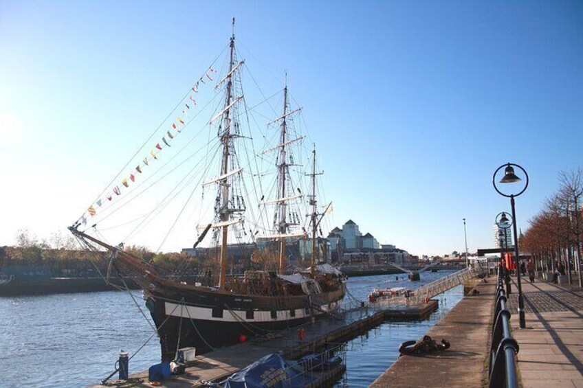 Ein großes Segelschiff liegt im Hafen vor Anker, der Himmel ist klar und im Hintergrund ist eine Brücke zu sehen. 2