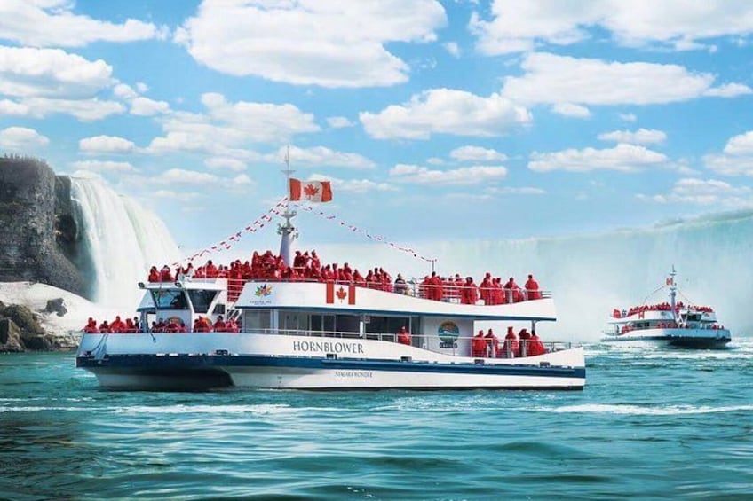 Two boats with red flags and passengers, near a waterfall. 2