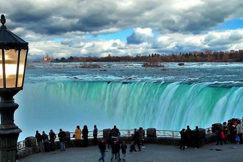 A waterfall, people, and a cloudy sky. 4