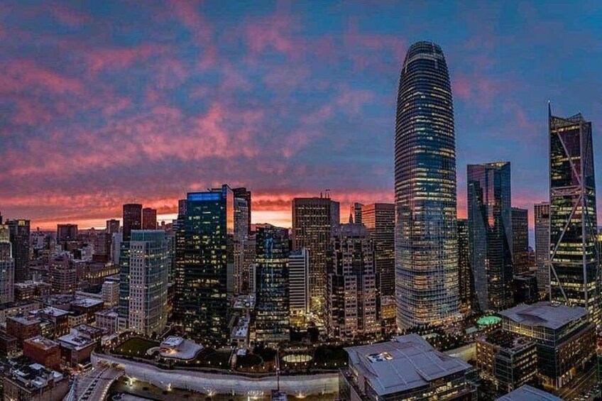 A city skyline at dusk with illuminated buildings and a sunset sky. 4