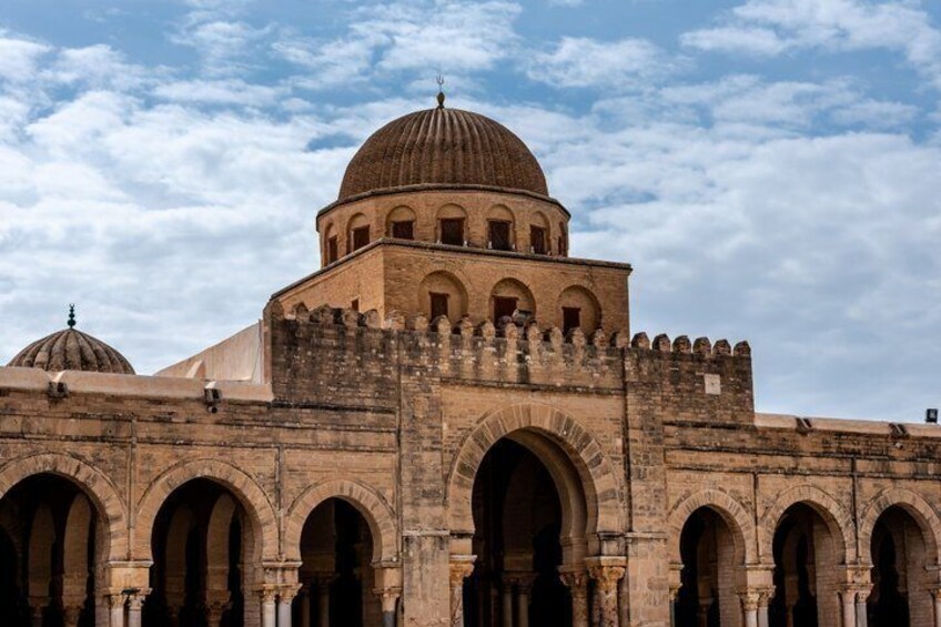 A historic building with a large dome and arched gateways. 1