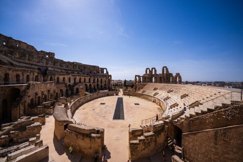 An ancient amphitheater with a central stage and tiered seating. 5