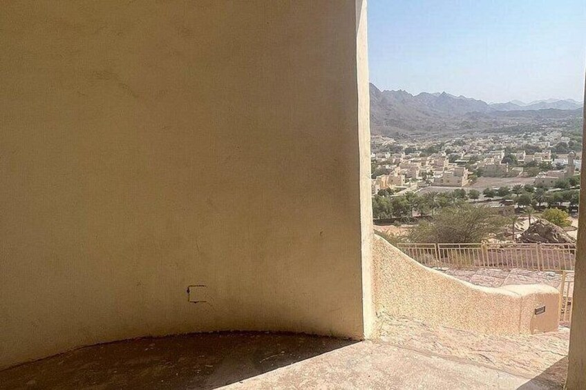 A balcony with a view of a town and mountains in the distance. 5