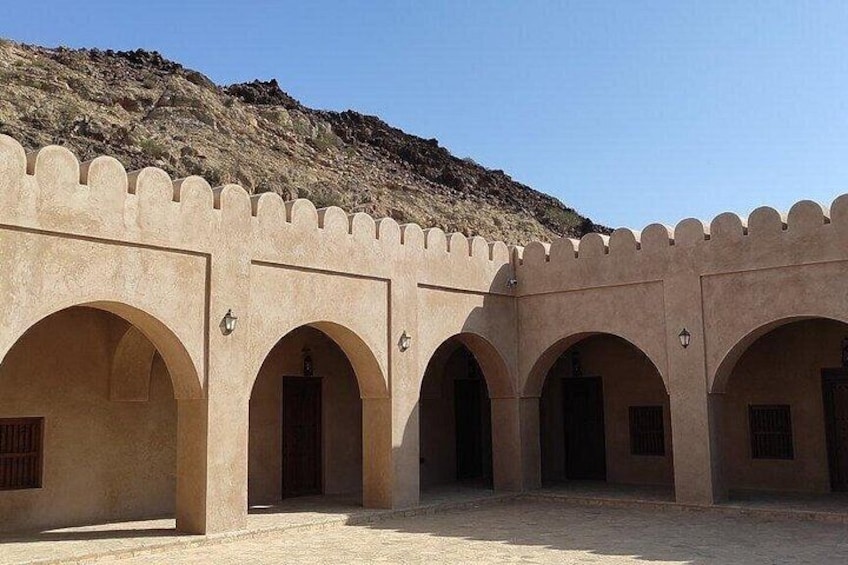 A series of arches in a courtyard with a mountainous backdrop. 1