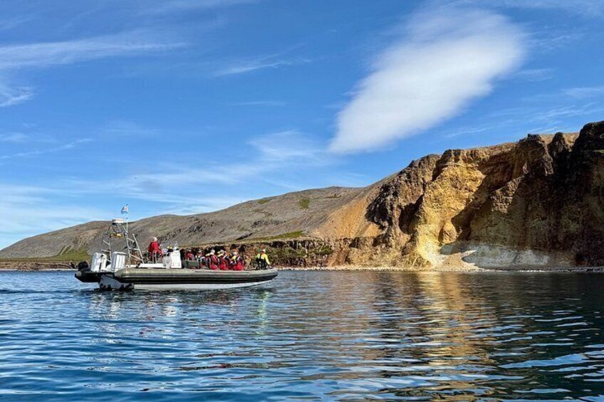 A boat with passengers near a rocky coastline. 3