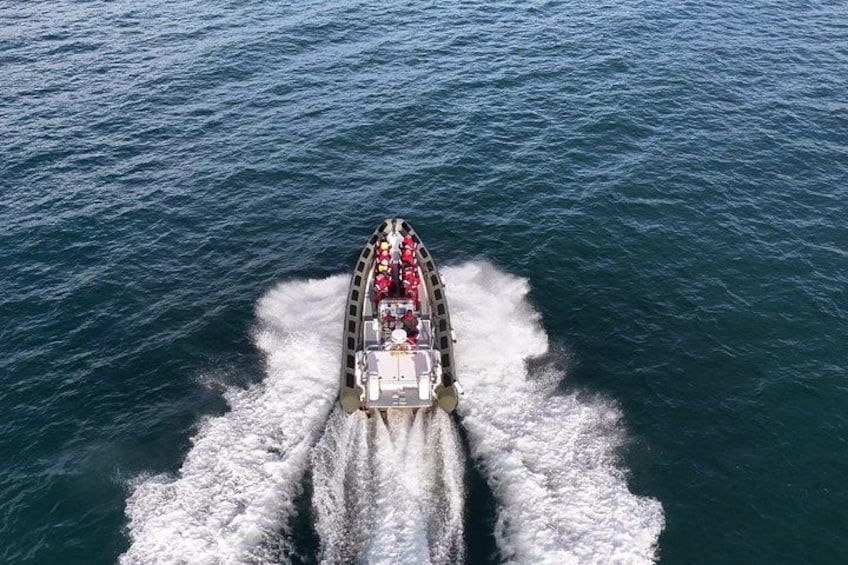 A speedboat with multiple passengers and a wake behind it on a large body of water. 5