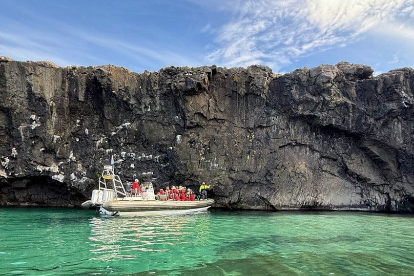 A boat with people on a rocky coastline. 1