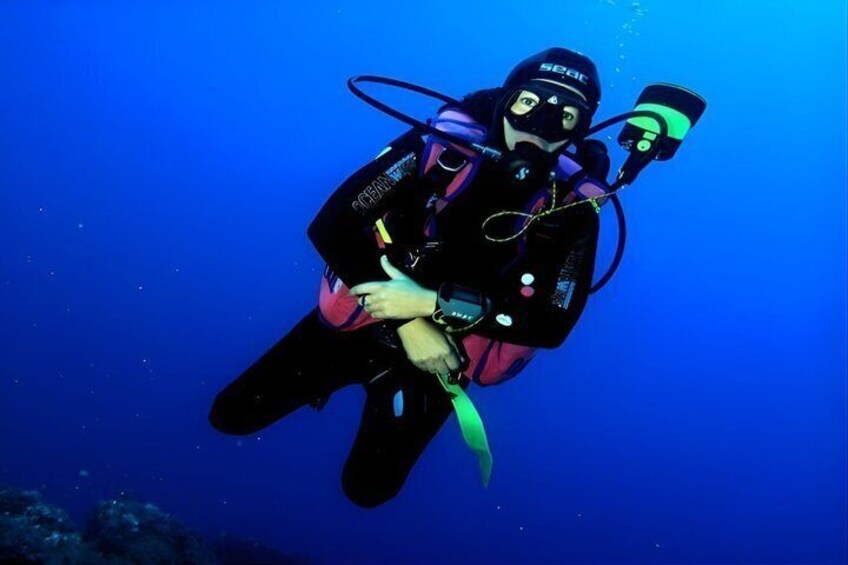 A diver in a black wetsuit with a helmet and oxygen tank, swimming underwater. 5