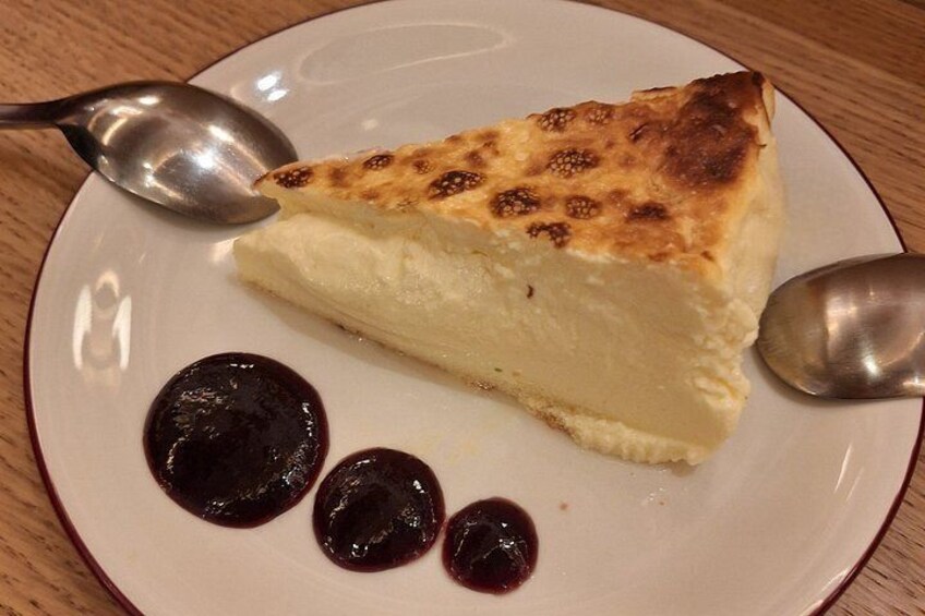 A slice of cheesecake on a plate with a spoon and three dollops of sauce. 5