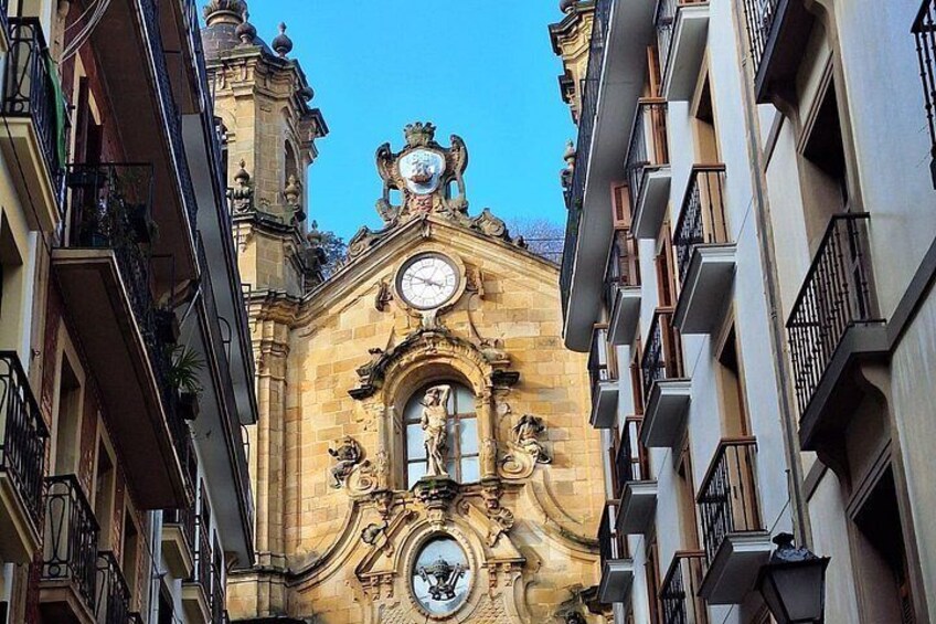 A historic building with ornate architecture, a clock, and a statue. 3