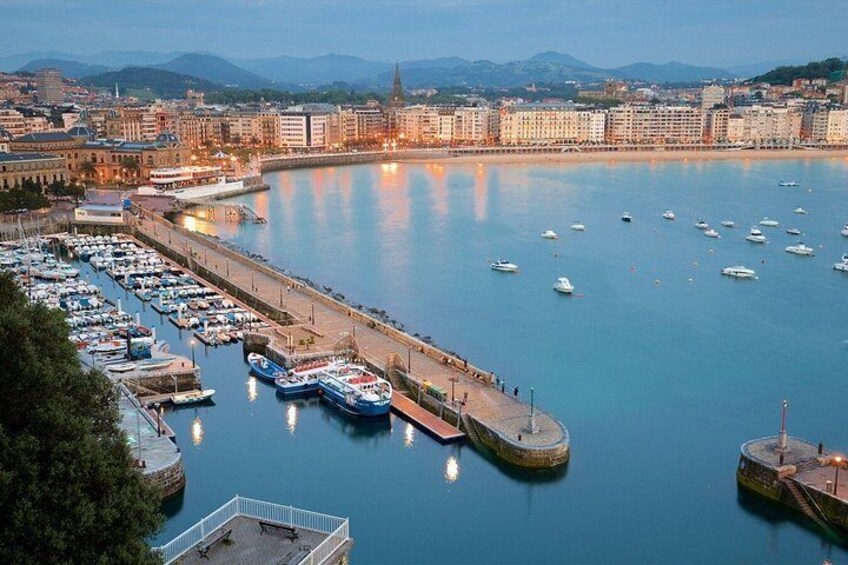 A marina with boats docked, a waterfront promenade, and a cityscape in the background. 2
