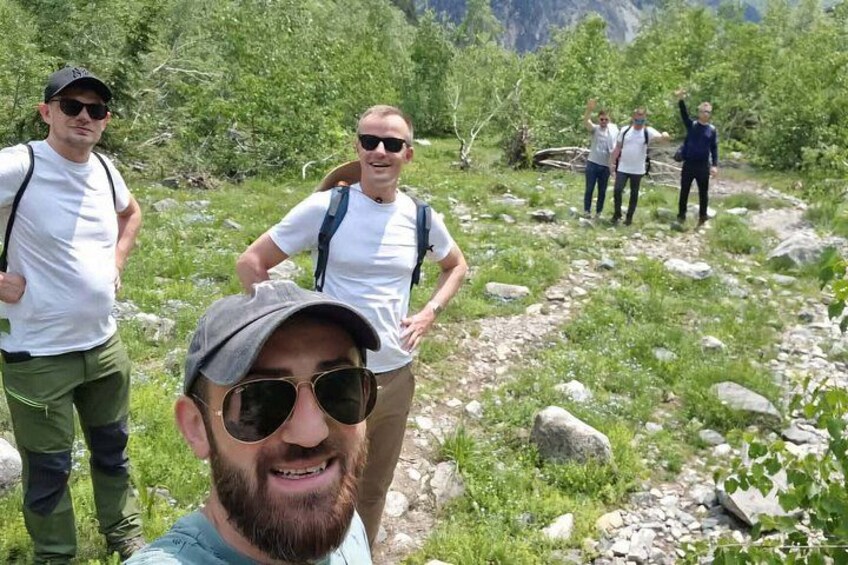 A group of people hiking on a rocky trail surrounded by greenery. 4
