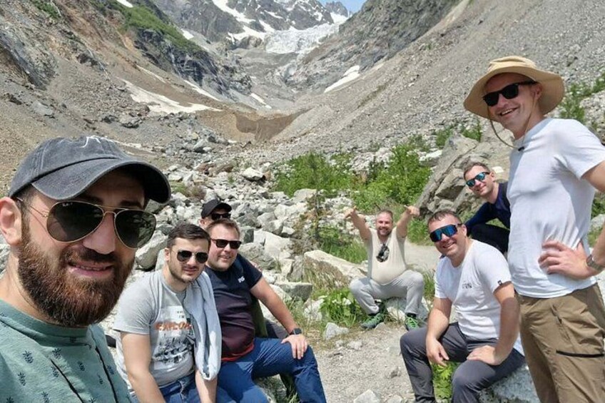 A group of people sitting on a rocky outcrop with a mountainous landscape in the background. 2