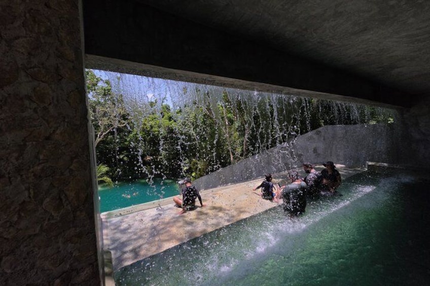 A pool with water jets, a concrete wall, and a forested area in the background. 3