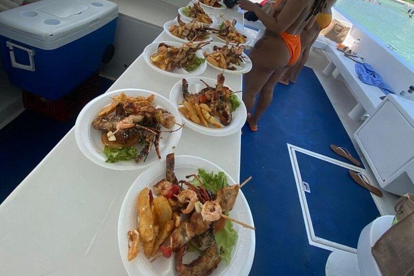 A table with seafood dishes, a cooler, and a poolside setting. 3