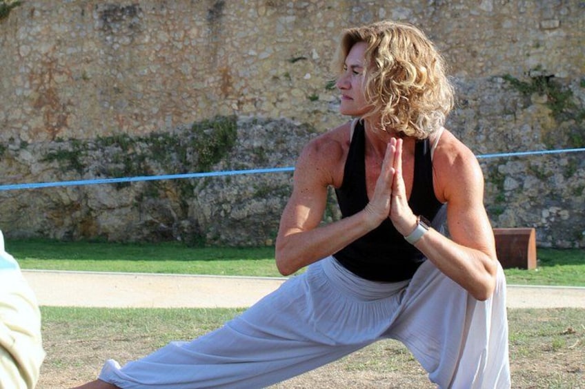 A person in a yoga pose outdoors with a stone wall in the background. 5