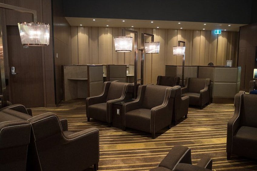 A hotel lobby with rows of armchairs, a reception desk, and wall-mounted lamps. 2