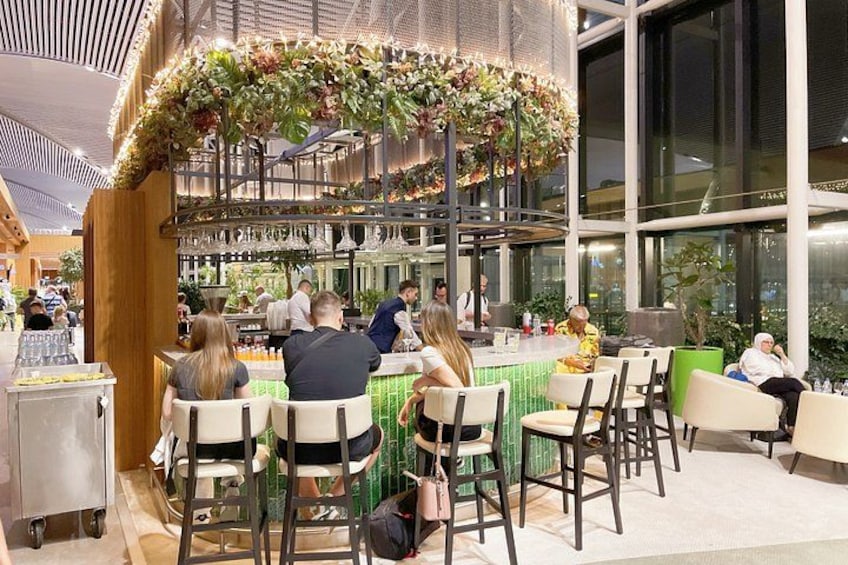Un restaurant doté d’un bar, avec des clients assis à des tables et une composition florale décorative au-dessus du bar. 4