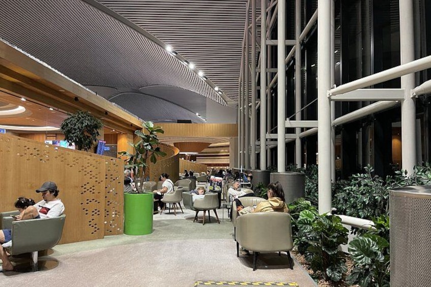 Un espace intérieur moderne doté de coins salon, de plantes et d’un plafond haut avec des poutres apparentes. 3