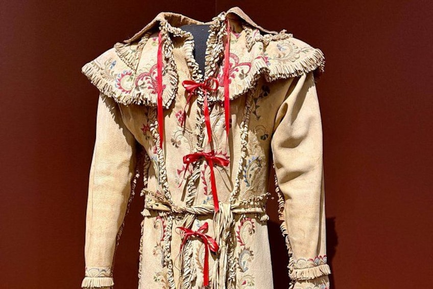 A traditional embroidered garment with intricate patterns and red ribbons. 3