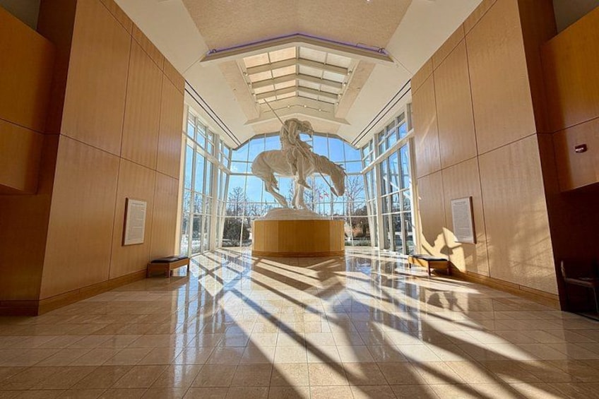 A spacious lobby with a large sculpture of a horse, wooden paneling, and a tiled floor. 4
