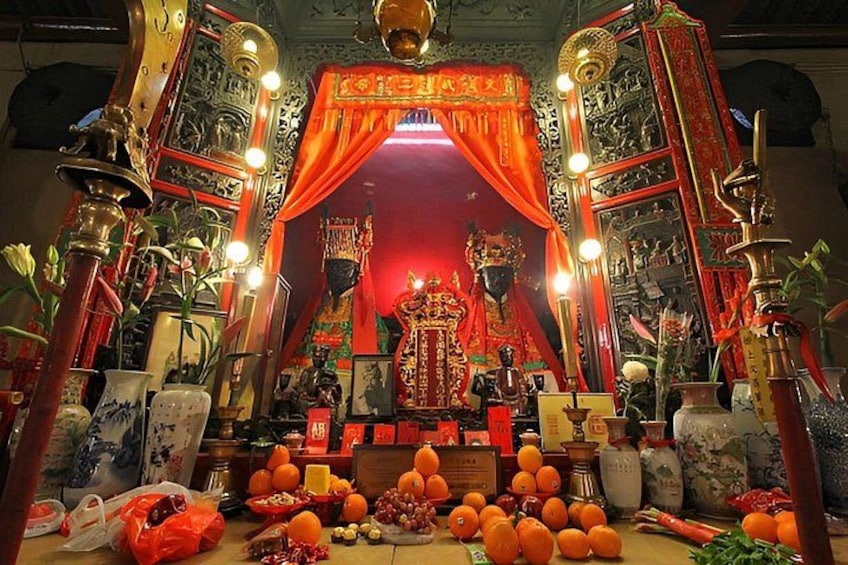 A traditional altar with red drapes, incense burners, and offerings. 3