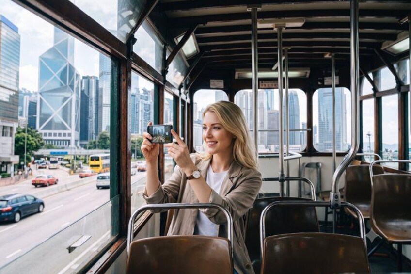 A person taking a photo inside a bus with a cityscape visible through the windows. 5