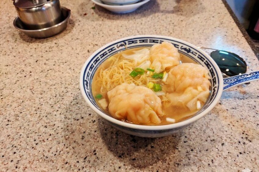 A bowl of soup with dumplings and noodles. 4