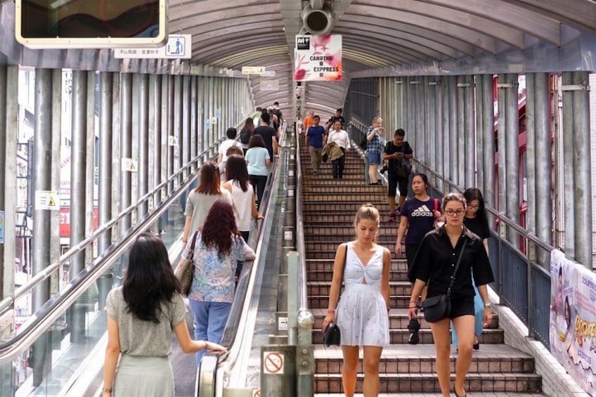 A pedestrian bridge with people walking and standing, metal railings, and a sign for Candine Express. 4