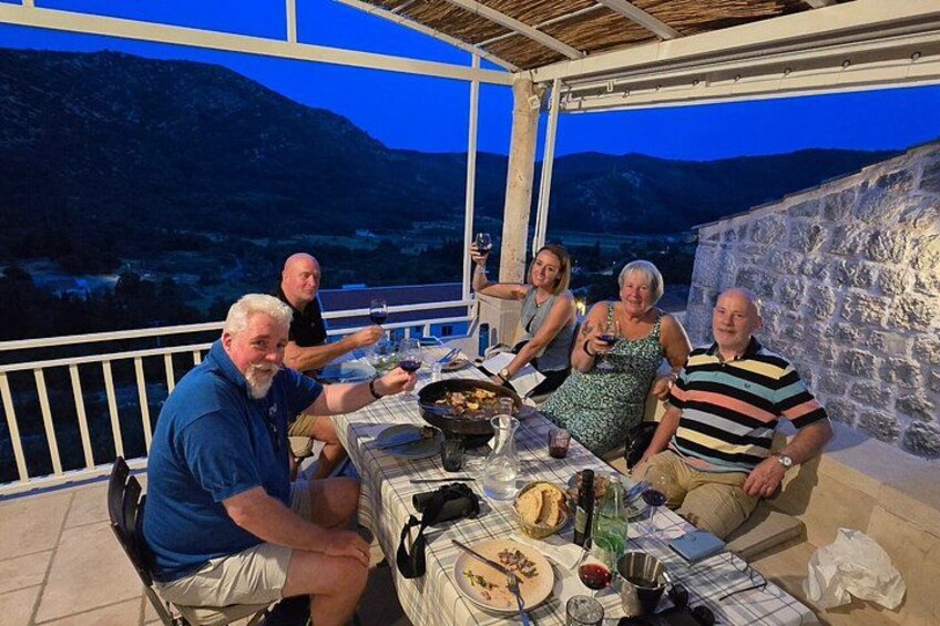 Un groupe de personnes est réuni autour d’une table à l’extérieur pour déjeuner, avec une chaîne de montagnes en toile de fond. 2