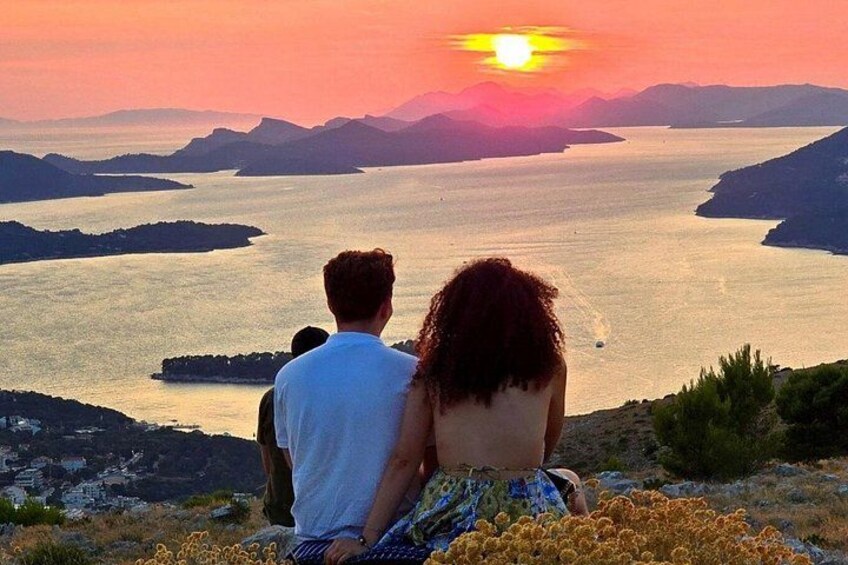 Una coppia seduta su una collina con vista su un lago al tramonto. 5