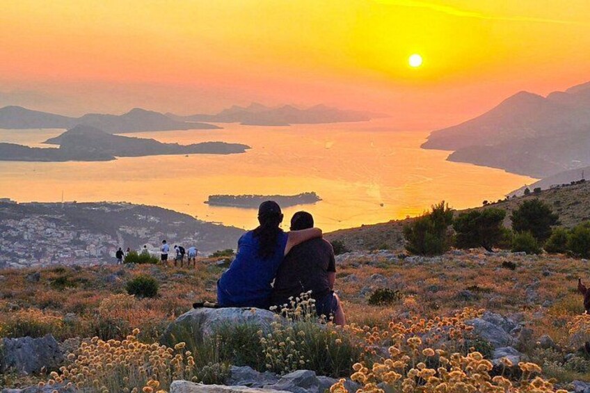 Tramonto su un paesaggio costiero con persone sedute sugli scogli e vista mare. 2