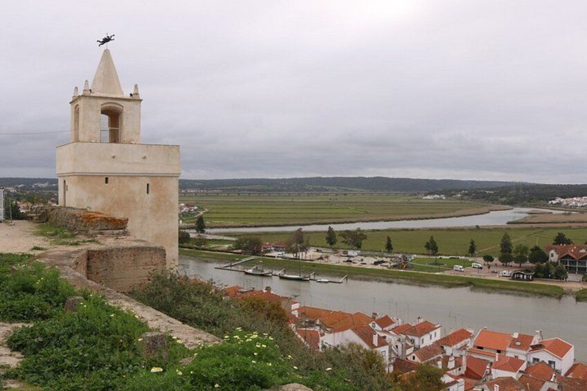 A tower, a river, and a town with red-roofed buildings. 4