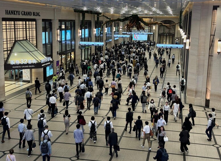 A busy indoor pedestrian area with people walking, signs, and a large hanging structure. 4