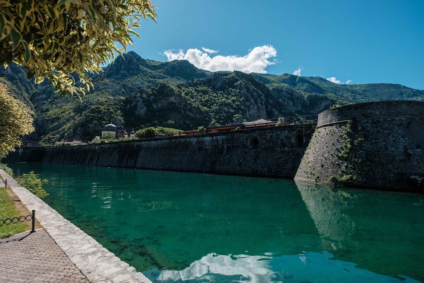 A clear lake with a stone wall and a mountain in the background. 5