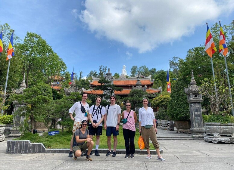 A group of people posing in front of a traditional temple with a statue on top. 5