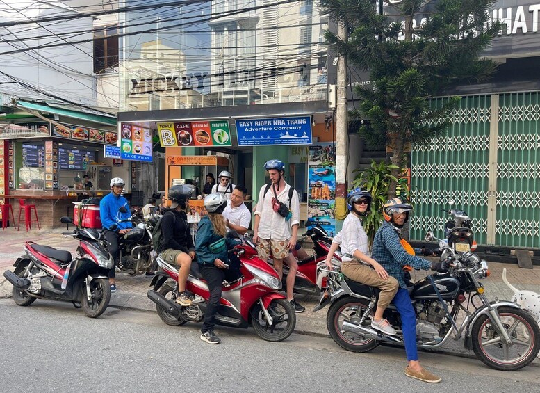 A street with motorbikes and people, a cafe, and a building with a sign. 2