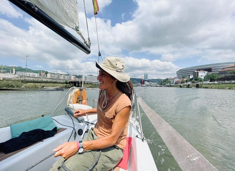 A person on a sailboat, wearing a hat, with a cityscape in the background. 3