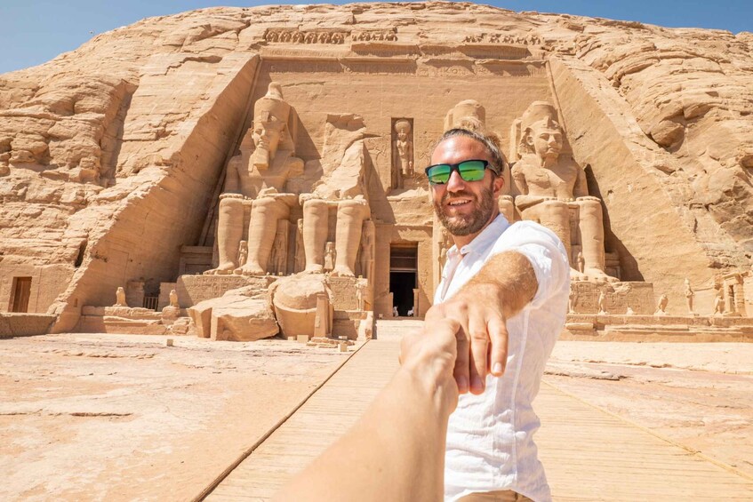 Henkilö seisoo suuren, muinaisen egyptiläisen temppelin edessä. Temppelissa on patsaita ja hieroglyfejä. 3