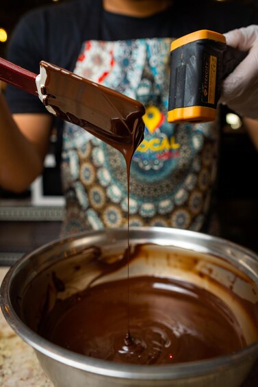 A person pouring chocolate from a container into a bowl. 4