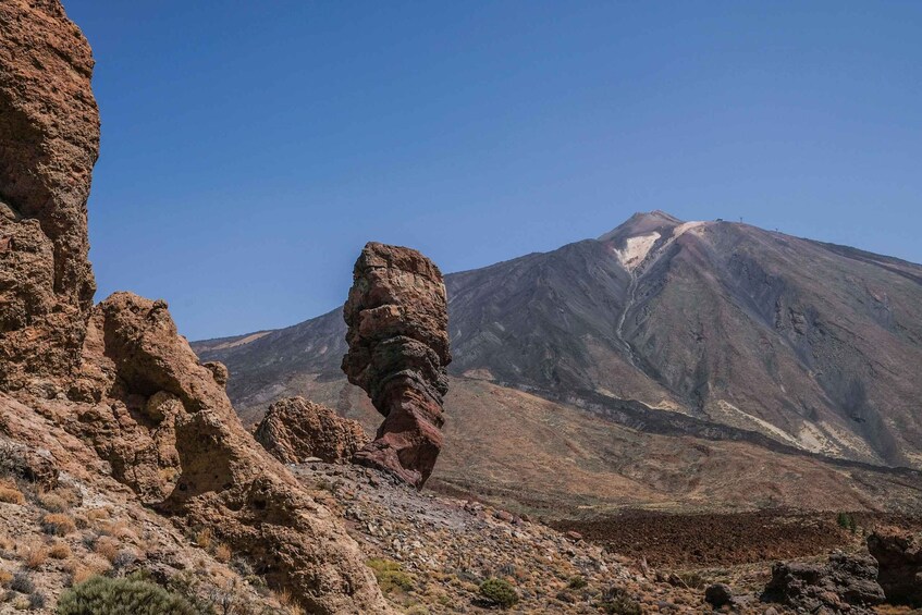 A rocky landscape with a prominent rock formation in the foreground and a mountain in the background. 1