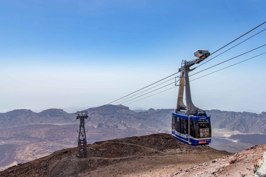 A cable car ascending a mountain with a clear sky. 2