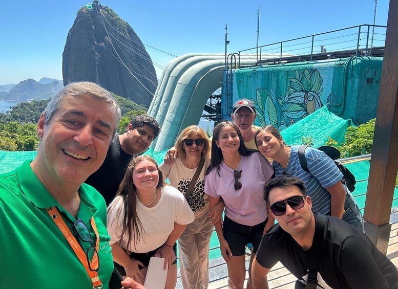 A group of people posing in front of a large water slide with a mountain in the background. 1