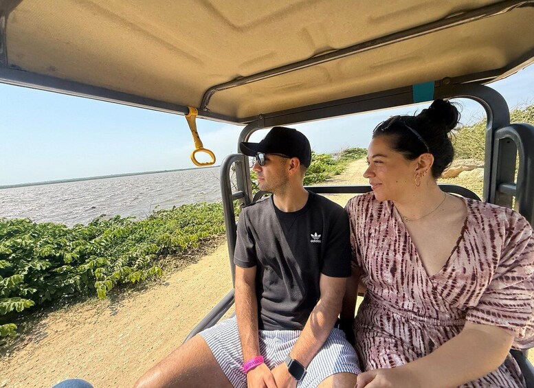 Two people seated in a vehicle with a view of a beach and ocean. 2